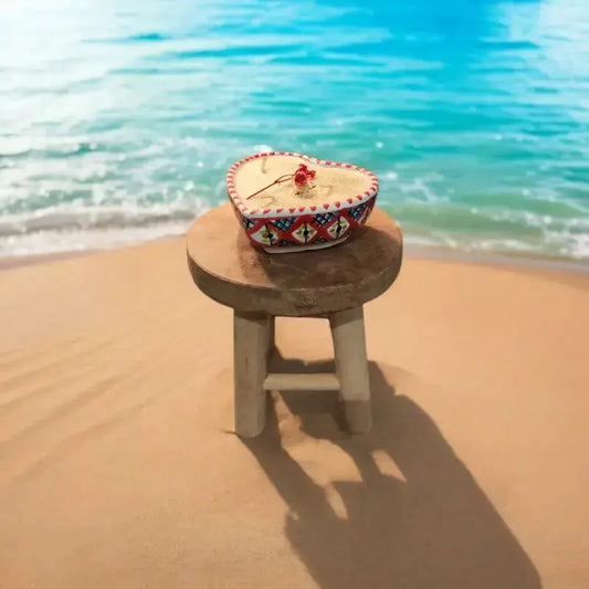 Bougie artisanale en forme de cœur céramique de Nabeul décorée posée sur un tabouret face a la mer