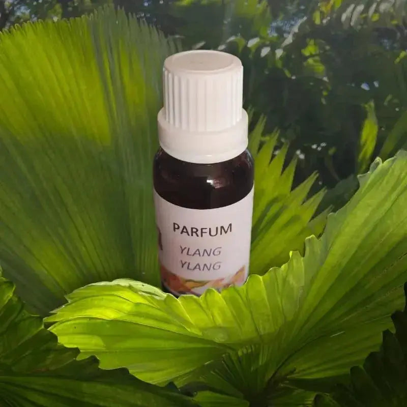 gros plan sur la fiole ambrée d’extrait parfum ylang ylang sur fond vert tropical