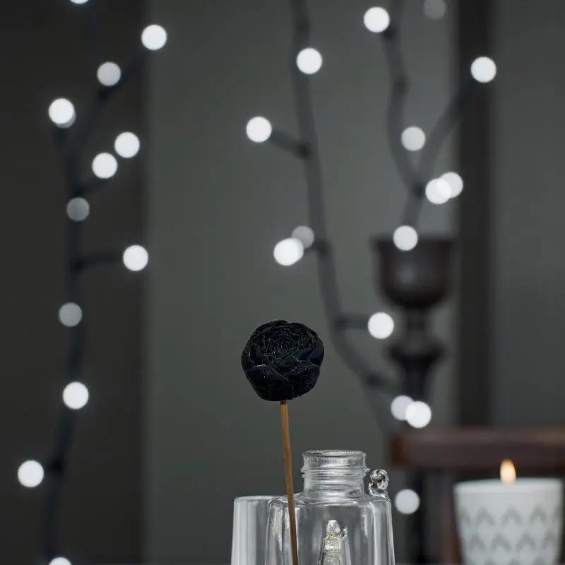 Petite renoncule noir en cire artisanale, fleur dans un pot en verre parmi des lumière blanche de noël  – Lulu Baladine