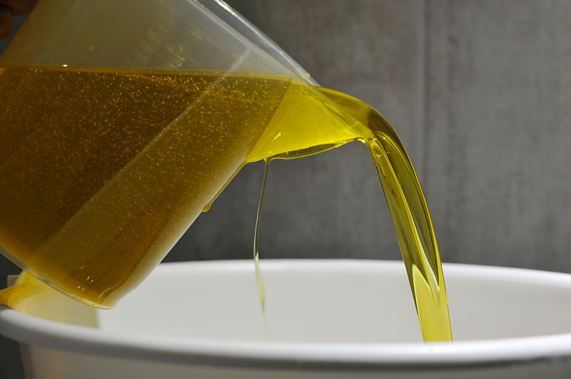 Coulage de l'huile d'olive dans un saladier blanc a l'aide d'un pichet 